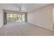 Bright, carpeted living room with sliding glass doors leading to a balcony, ceiling fan and neutral paint at 407 Bouchelle Dr # 205, New Smyrna Beach, FL 32169