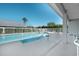A pool surrounded by an ample concrete deck with a handrail and a view of palm trees at 549 Coral Trace Blvd, Edgewater, FL 32132