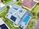 Aerial view of a single-Gathering home featuring solar panels, screened lanai, lush landscaping, and a private pool at 6665 Merryvale Ln, Port Orange, FL 32128