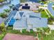 Aerial view of a home with a gray roof, screened pool, beautiful landscaping, and lake view at 6665 Merryvale Ln, Port Orange, FL 32128