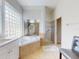 Bathroom featuring a soaking tub with glass block window, and separate tiled shower at 6665 Merryvale Ln, Port Orange, FL 32128