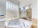 Bathroom showcasing soaking tub with glass block window, tile surround, and separate glass-enclosed shower at 6665 Merryvale Ln, Port Orange, FL 32128