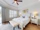 Bright bedroom with tray ceiling, ceiling fan, wood floors, shuttered window, and an upholstered bench at 6665 Merryvale Ln, Port Orange, FL 32128