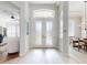 Bright foyer features white double doors with decorative glass and light wood-look flooring throughout at 6665 Merryvale Ln, Port Orange, FL 32128
