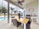 Covered patio featuring a dining table, grill, and serene views of the pool and lake beyond the screened enclosure at 6665 Merryvale Ln, Port Orange, FL 32128