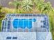 Aerial view of a kidney-shaped pool inside a screened lanai, surrounded by lush tropical landscaping at 6665 Merryvale Ln, Port Orange, FL 32128