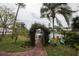 Lush backyard with a charming vine-covered archway, leading to patio furniture with a pond view at 731 Pine Shores Cir, New Smyrna Beach, FL 32168