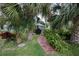 Lush backyard with a winding stone path, surrounded by palms and greenery, leading to a charming outdoor space at 731 Pine Shores Cir, New Smyrna Beach, FL 32168