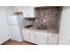 A detailed view of a compact kitchen with white cabinetry, granite countertops, and modern appliances at 746 N Halifax Ave, Daytona Beach, FL 32118