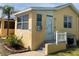 Charming home exterior featuring a small porch, palm trees, and a bright yellow facade at 835 E 24Th Ave # 111, New Smyrna Beach, FL 32169