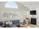 Sunlit living room with vaulted ceilings, coastal art, a gray sectional sofa, and a fireplace, creating a relaxing atmosphere at 898 Baybreeze Way # 880, New Smyrna Beach, FL 32169