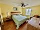 Cozy bedroom with wooden floors, ceiling fan, bright yellow walls, and natural light from the window at 112 Lagoon Ct, New Smyrna Beach, FL 32169