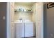 Functional laundry room with washer, dryer and shelving behind white louvered doors at 2689 Sicily Dr, New Smyrna Beach, FL 32168
