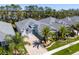 Aerial view of the home's front, featuring a well-kept lawn, palm trees, and paver driveway at 3045 Borassus Dr, New Smyrna Beach, FL 32168