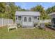 Close up of a gray storage shed featuring seating, mature trees, and landscaping at 312 Jefferson Ave, Port Orange, FL 32127