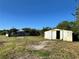 Exterior view of weathered outbuildings, surrounded by an unkempt grassy yard and clear blue sky at 3890 Skyway Dr, Sanford, FL 32773
