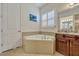 Bathroom featuring a soaking tub, shuttered window, granite vanity and brown wood cabinets at 465 White Cotton Cir, Oviedo, FL 32765