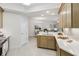 Bright kitchen with white countertops, tan cabinets and an open view into the dining and living areas at 7 Riverwalk Dr # 206, New Smyrna Beach, FL 32169
