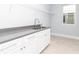 Convenient laundry room features white cabinetry with grey countertops, stainless steel sink, and lots of natural light at 113 Douglas St, Edgewater, FL 32141