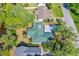 Aerial view of home and backyard, featuring mature trees, green roof, and lush landscaping at 1227 Wayne Ave, New Smyrna Beach, FL 32168