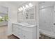 Bathroom featuring double sink vanity with mirrors and walk-in tiled shower at 1227 Wayne Ave, New Smyrna Beach, FL 32168