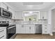 Well-lit kitchen boasting updated appliances, white cabinetry and a stone backsplash at 1227 Wayne Ave, New Smyrna Beach, FL 32168