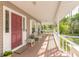 Charming front porch with comfortable seating, a red door, and lush landscaping creates a welcoming entrance at 1910 Botree Ct, Port Orange, FL 32128