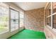 Inviting enclosed front porch featuring stone accent wall and green carpet at 3635 Scott St, Port Orange, FL 32129