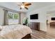Comfortable main bedroom with ceiling fan, large window, and sleek television above a wood dresser at 532 White Coral Ln, New Smyrna Beach, FL 32168
