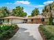 Charming single-story ranch-style home featuring a large driveway, mature trees, and well-maintained landscaping at 56 Live Oak Ln, New Smyrna Beach, FL 32168