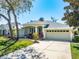 Charming single-story home featuring a manicured lawn, mature landscaping, and attached two-car garage at 5986 Heron Pond Dr, Port Orange, FL 32128