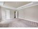 A neutral bedroom with a tray ceiling, recessed lighting, and ensuite bathroom access at 1012 Bradford Ridge Dr, Leesburg, FL 34748