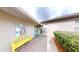 Charming front porch with bright yellow bench, brick pavers, and colorful tropical art at 106 Tuscany Villas Dr # 0160, Edgewater, FL 32141