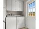 Functional laundry area with washer, dryer, overhead cabinets, and a door to the outside at 121 Ellicott Dr, Ormond Beach, FL 32176
