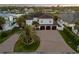 Aerial view of a two-story home with palm trees, a three-car garage, and waterfront views at 1212 Commodore Dr, New Smyrna Beach, FL 32168