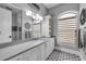 Modern bathroom features a marble countertop, dual windows, and a gray and white decorative tile floor at 1212 Commodore Dr, New Smyrna Beach, FL 32168