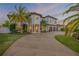 Stunning two-story home with a three-car garage, palm trees, and a circular driveway at sunset at 1212 Commodore Dr, New Smyrna Beach, FL 32168