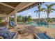 Inviting covered patio area with comfortable seating, overlooking a sparkling pool and lush tropical landscaping at 1212 Commodore Dr, New Smyrna Beach, FL 32168