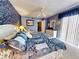 Inviting bedroom with blue accent wall, ceiling fan, dresser, and plush patterned bedspread at 133 Cedar Dunes Dr, New Smyrna Beach, FL 32169