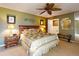 Green main bedroom featuring a ceiling fan, nightstands with lamps, a king bed, and an ensuite bathroom at 133 Cedar Dunes Dr, New Smyrna Beach, FL 32169