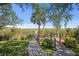 Scenic marsh view from a wooden dock and a stone path with palms and mature trees at 1363 Wayne Ave, New Smyrna Beach, FL 32168