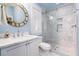 Modern bathroom with a round gold mirror, white vanity, and a glass-enclosed shower, offering a spa-like experience at 1373 N Atlantic Ave, New Smyrna Beach, FL 32169