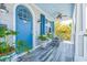 Inviting front porch with a vibrant blue door, wood-look flooring, plants and rocking chairs at 1373 N Atlantic Ave, New Smyrna Beach, FL 32169