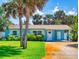 Charming blue home featuring a well-maintained lawn, palm trees, and a bright white front door at 16 Hillside Dr, New Smyrna Beach, FL 32169