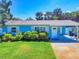 A well-manicured lawn compliments this charming, light blue single story home with covered parking at 16 Hillside Dr, New Smyrna Beach, FL 32169