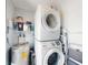 Laundry room featuring stackable washer and dryer, water heater and wire shelving at 16 Hillside Dr, New Smyrna Beach, FL 32169