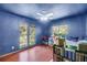 Bright bedroom with unique blue walls, ceiling fan, and views of the surrounding landscape at 1663 Hideaway Ln, Edgewater, FL 32132