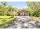 Welcoming home exterior, featuring stone detailing, with a long drive, set amidst a backdrop of mature trees at 1663 Hideaway Ln, Edgewater, FL 32132