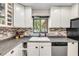 This view of the kitchen highlights white cabinets, brick backsplash, and stainless steel appliances at 1663 Hideaway Ln, Edgewater, FL 32132
