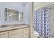 Bright bathroom features granite counters, a large mirror, and a shower behind a stylish curtain at 1855 Pine Tree Dr, Edgewater, FL 32141